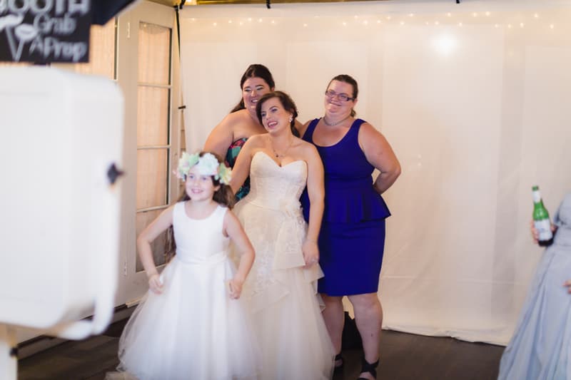 The bride Holly poses with two women and a flower girl in a white dress with a floral crown at Kwila Lodge during the reception stage.