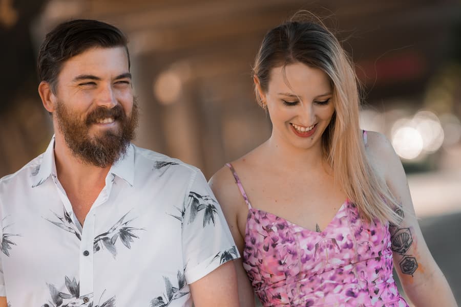 Close-up of the couple smiling at each other under a covered walkway, with soft light highlighting their expressions.