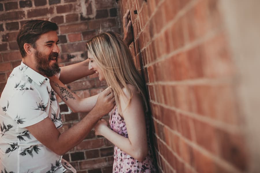 The couple laughing together, leaning against a brick wall, enjoying each other's company at Brisbane Powerhouse.