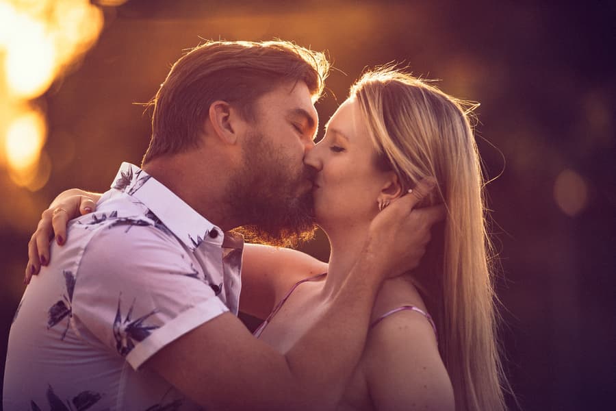The couple sharing a kiss, bathed in warm sunset light at Brisbane Powerhouse.