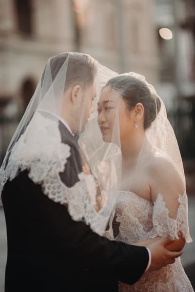 Aria and Antony stand close together under Aria's lace veil. Wedding photographers in Brisbane by She Said Yes.