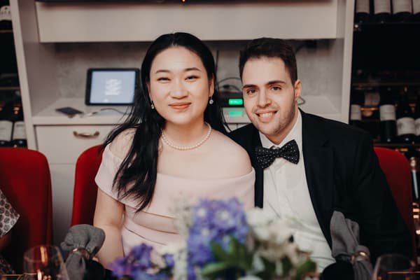 The bride Aria and the groom Antony sit together at a table during the reception at Donna Chang, with floral centerpieces and wine bottles visible in the background.