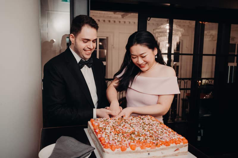 Aria and Antony cut a large rectangular wedding cake together at the reception stage in Donna Chang.