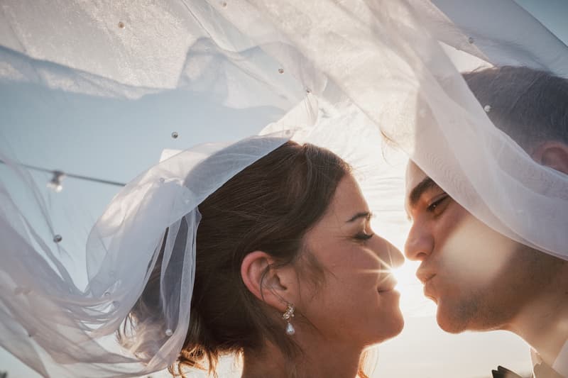 The bride Ashleigh and groom James pose closely under the bride's veil at Sandstone Point Hotel during their couple portraits session.