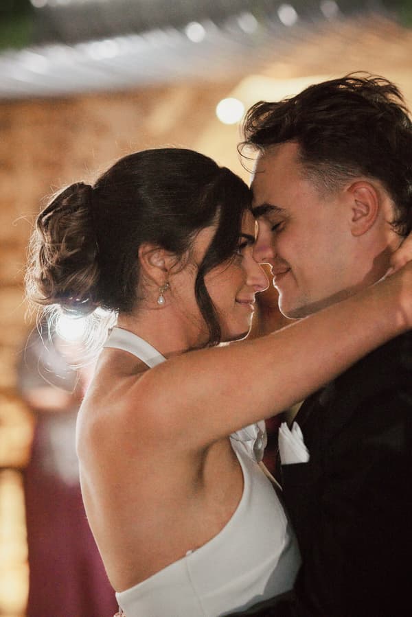 Bride Ashleigh and groom James embrace closely during a dance at the reception in Sandstone Point Hotel — The Cellar.