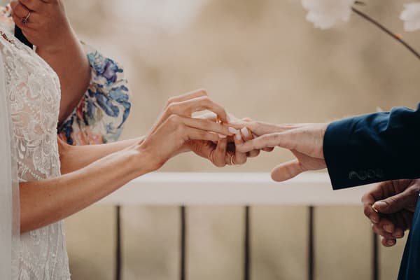 Courtney places a wedding ring on Cameron's finger during the ceremony at Sandstone Point Hotel — Pavilion.