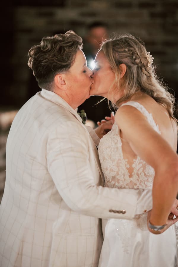 Brides Mandy and Selina share a kiss on the reception stage at Sandstone Point Hotel — The Cellar.