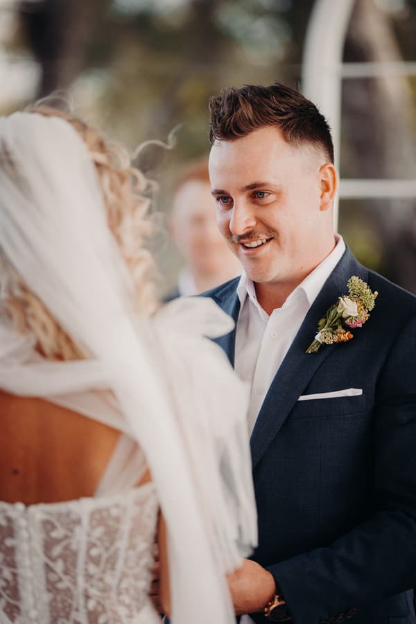 Brandon, the groom, looks at Krystal, the bride, during their wedding ceremony at Sandstone Point Hotel — Pavilion.