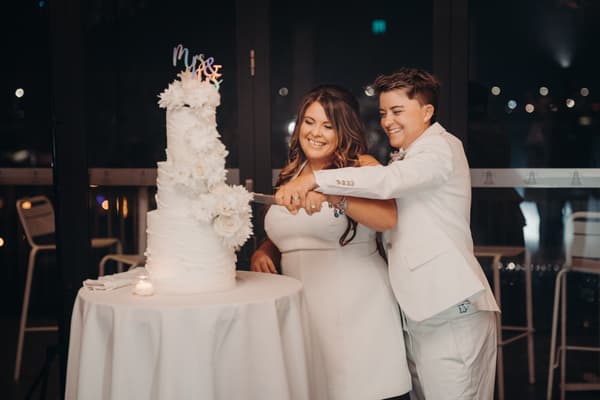 Brides Brooke and Tiffany cut their wedding cake together at the reception in The Pumicestone Room, Sandstone Point Hotel.