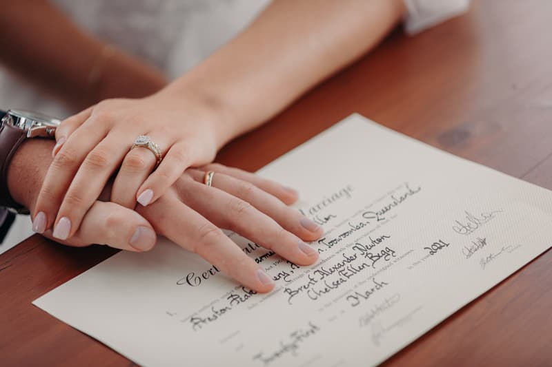 The bride Chelsea and groom Brent place their hands on their signed marriage certificate at Preston Peak Winery Functions Centre.