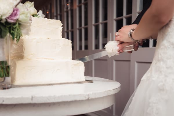 The bride and groom cut their three-tiered white wedding cake together at Hillstone St Lucia — The Rosewood Room.