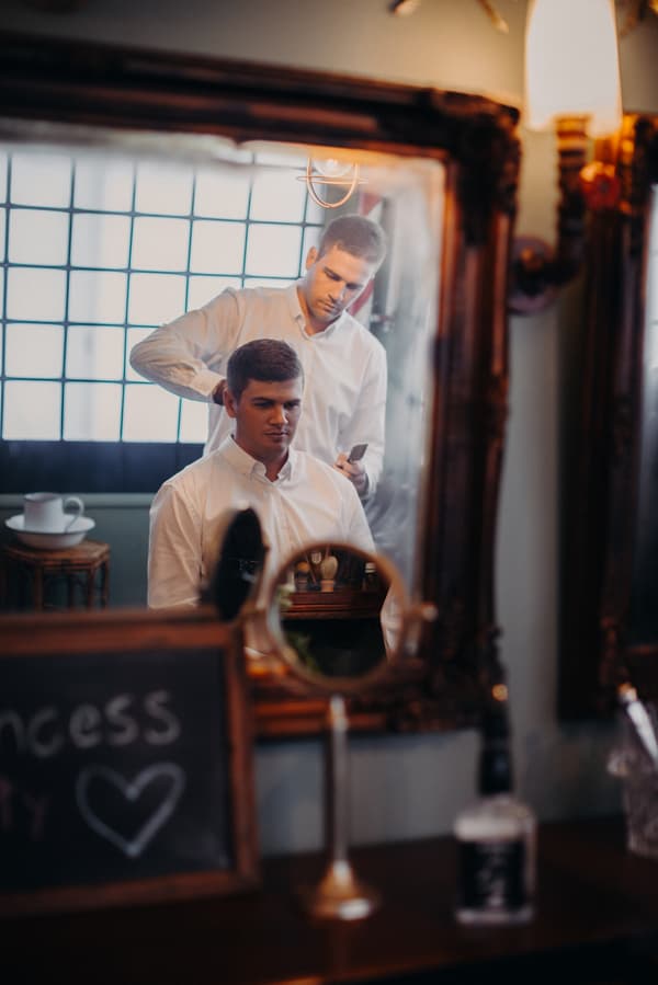 Reflection in a mirror showing Brent having his hair styled by another man at Preston Peak Winery Functions Centre.