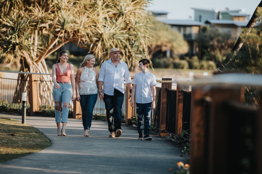 A family of four walks along a path, surrounded by greenery, enjoying a sunny day at Novotel Twin Waters.