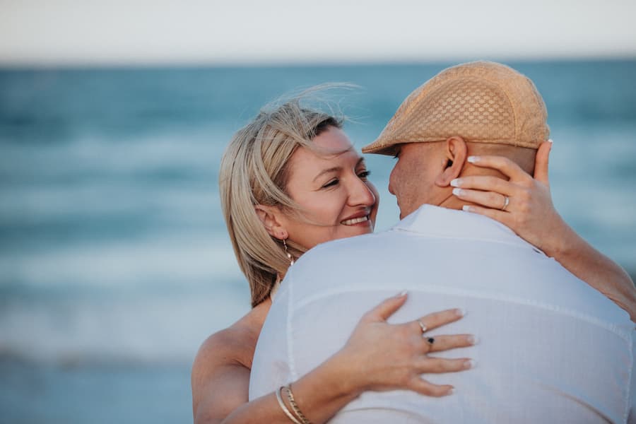 Close-up of the couple embracing and smiling at each other by the ocean at Novotel Twin Waters.