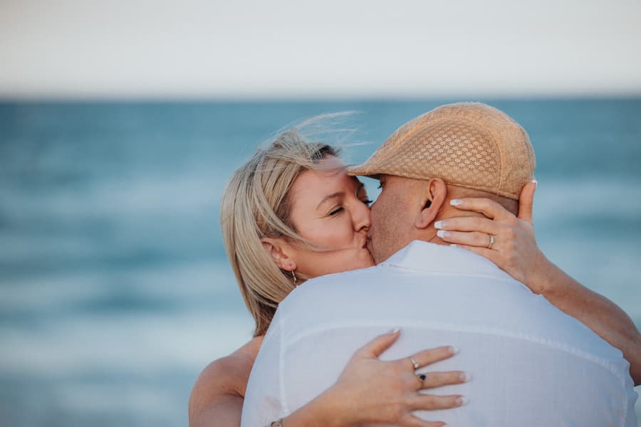 The couple kissing closely with the ocean in the background at Novotel Twin Waters.
