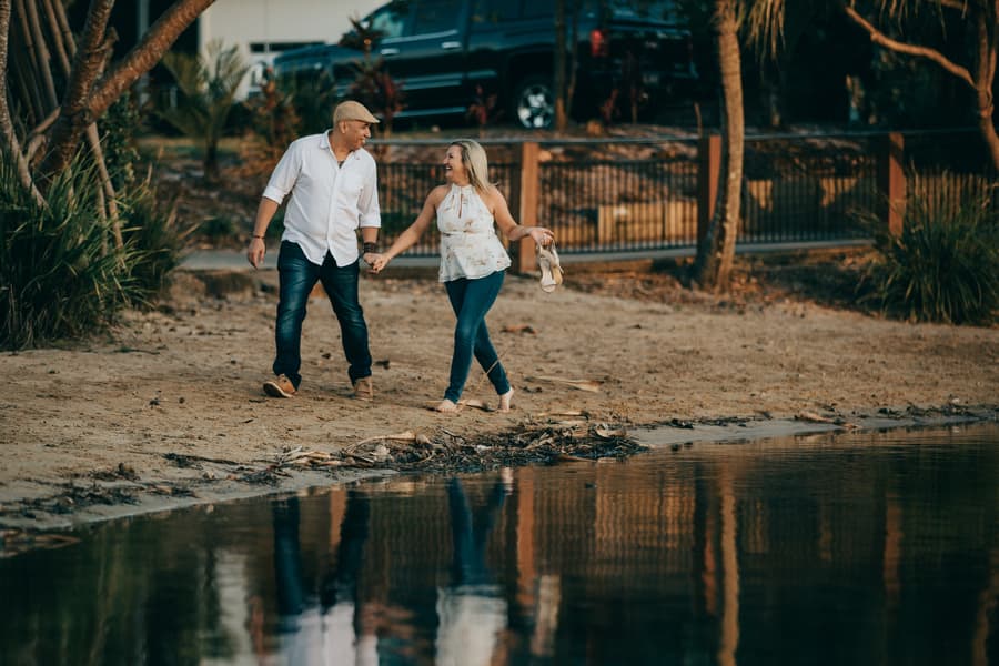 The couple walking hand in hand along a sandy path near water at Novotel Twin Waters.