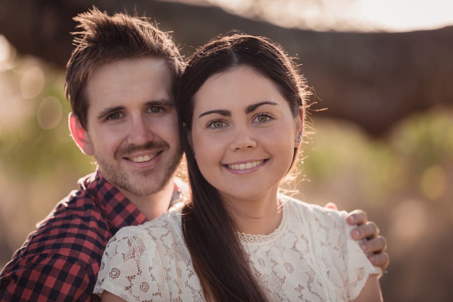 Close-up of the couple smiling at the camera, with the sun softly illuminating their faces.