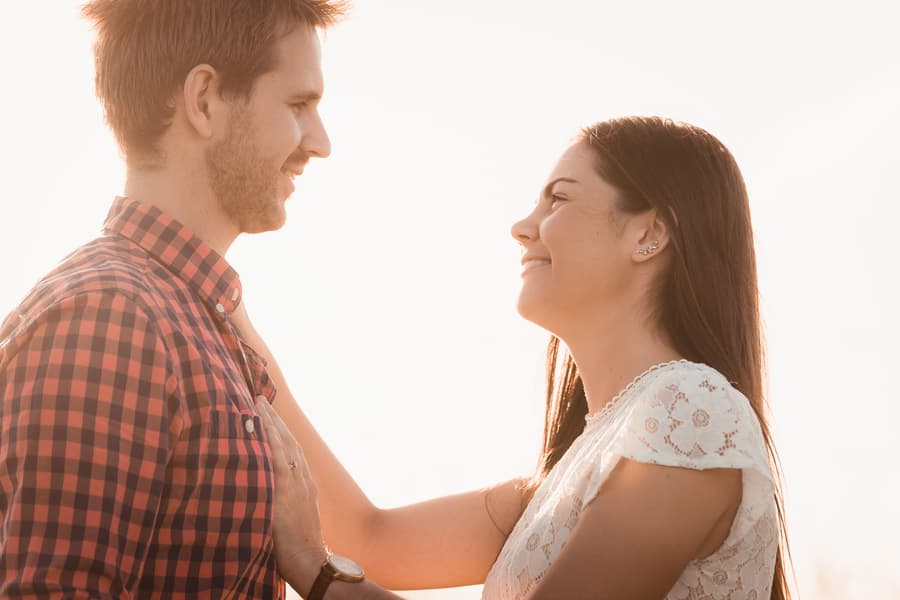 The couple gazes into each other's eyes, smiling warmly in the bright sunlight.