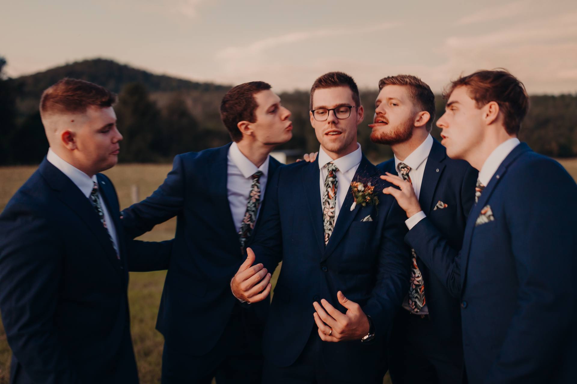 Connor, the groom, stands with four groomsmen outdoors at Yabbaloumba Retreat, all wearing matching navy suits and floral ties.