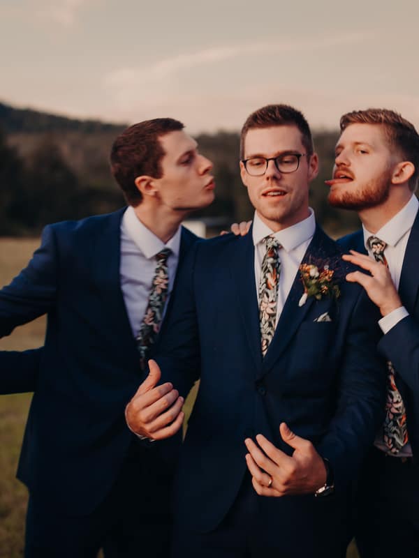 Connor, the groom, stands with four groomsmen outdoors at Yabbaloumba Retreat, all wearing matching navy suits and floral ties.