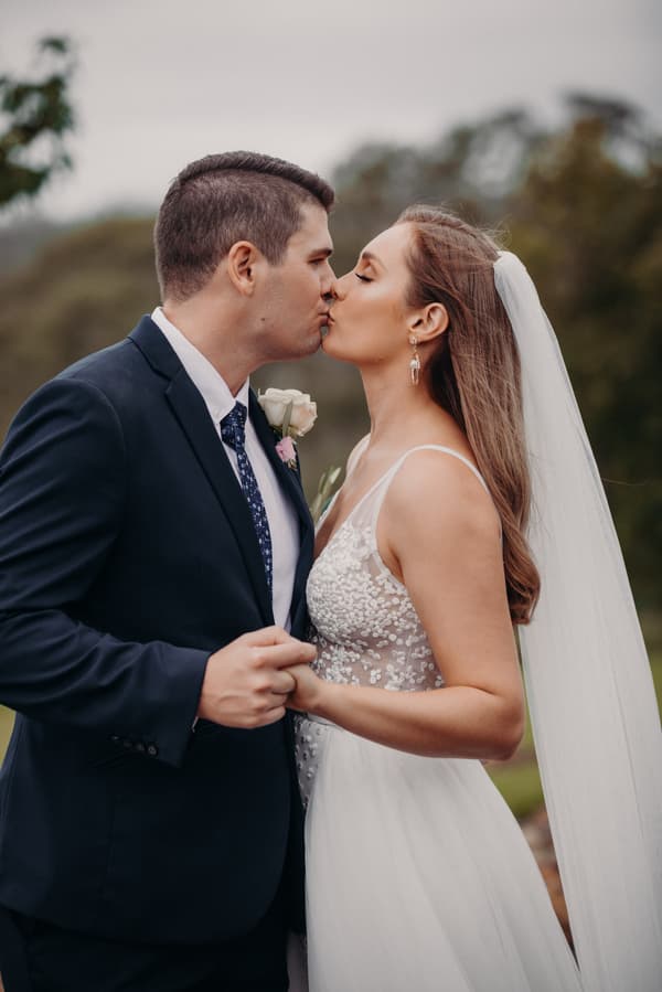 Chelsea and Brent share a kiss while holding hands during their couple portraits at Preston Peak Winery Functions Centre.