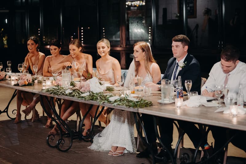 Chelsea the bride and Brent the groom sit at the head table with bridesmaids and a groomsman during the reception at Preston Peak Winery Functions Centre.