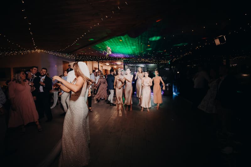 Chelsea, the bride, prepares to toss her bouquet to a group of bridesmaids and female guests at the Preston Peak Winery Functions Centre reception.