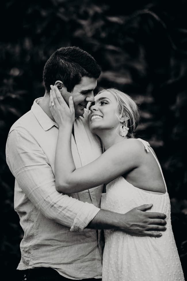 The couple shares a tender moment, gazing into each other's eyes with joy, in a black and white photo.