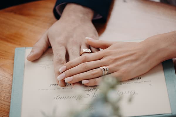 The bride Courtney and groom Cameron show their wedding rings resting on a marriage certificate at Sandstone Point Hotel — Pavilion.