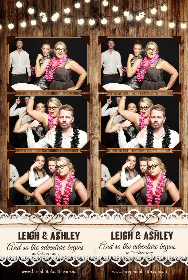 Guests posing with props, wearing leis and glasses in a photo booth.