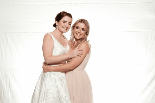Bride and bridesmaid embracing in a photo booth.