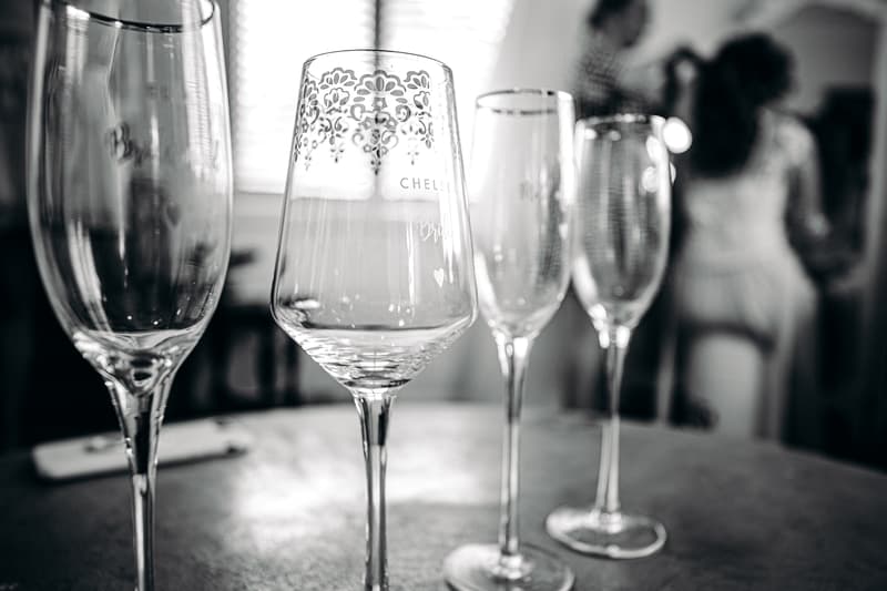 Four empty wine glasses on a table at Preston Peak Winery Functions Centre with a blurred background showing a bride and another person.