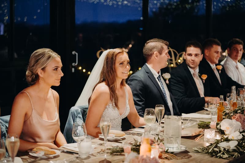 Chelsea the bride and Brent the groom sit at the head table with their wedding party during the reception at Preston Peak Winery Functions Centre.