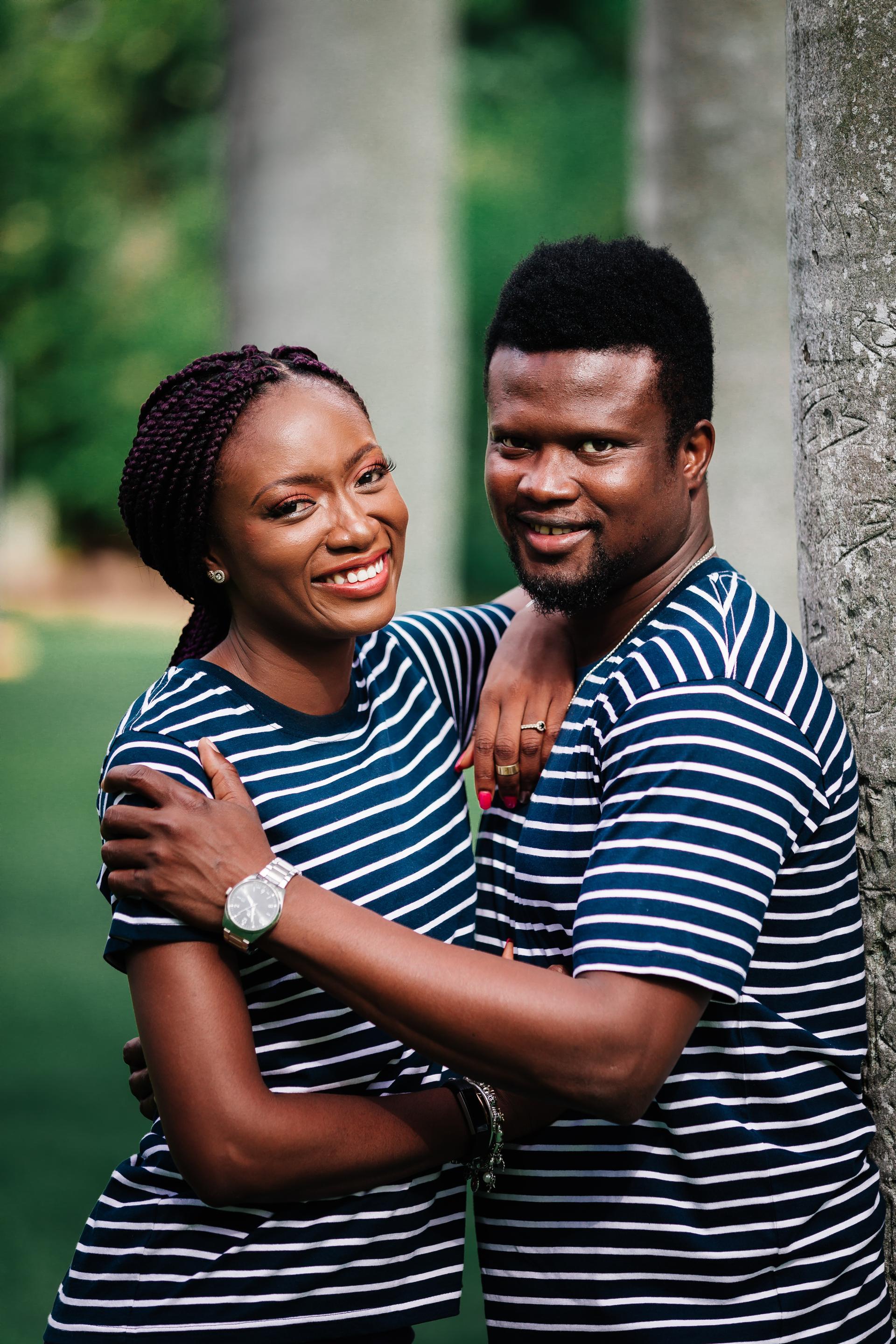 The couple in matching striped shirts embrace and smile at the camera, standing by a tree in Brisbane's City Botanic Gardens.