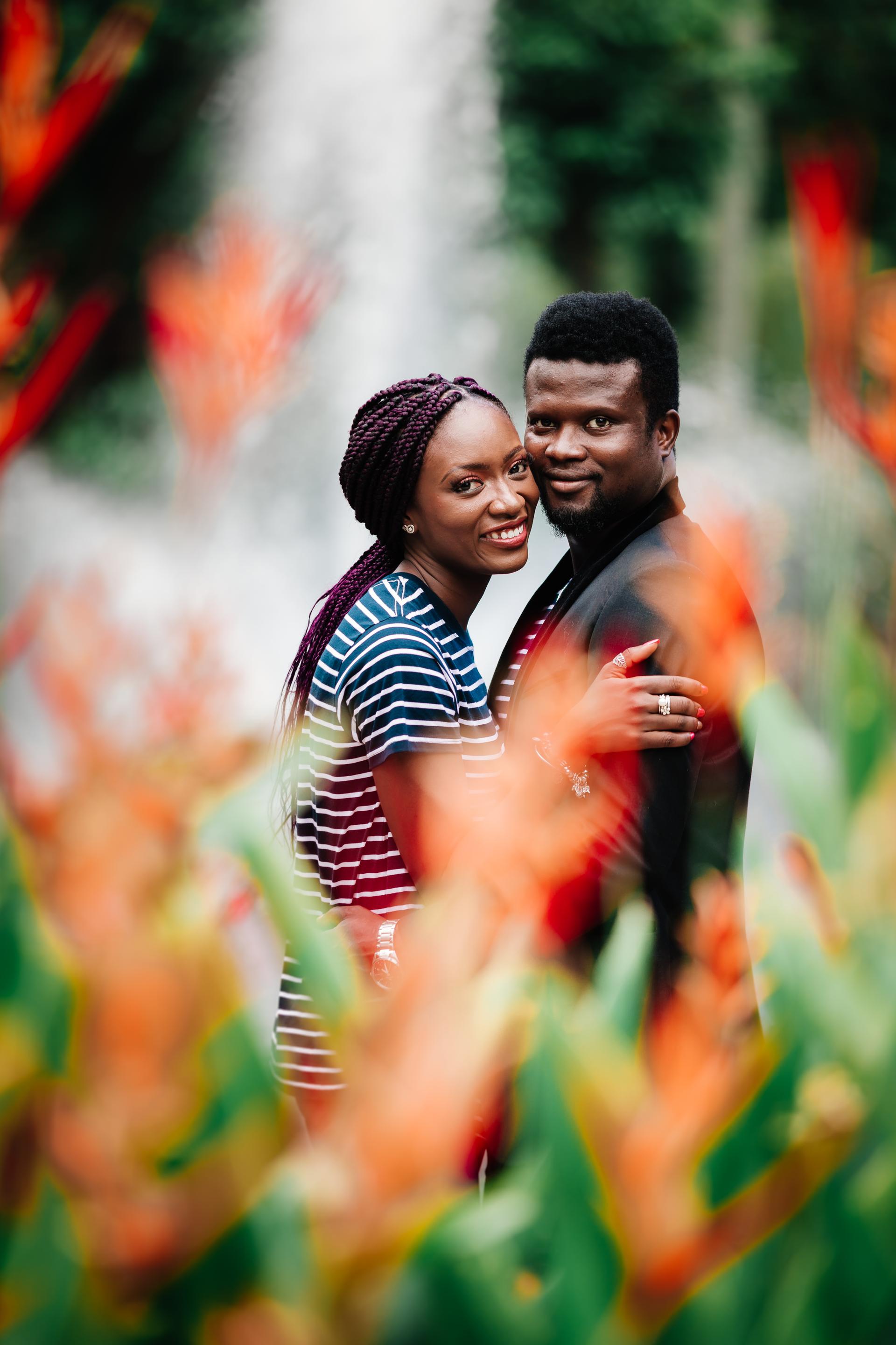 The couple embraces amidst colorful flowers, smiling at the camera in Brisbane's City Botanic Gardens.