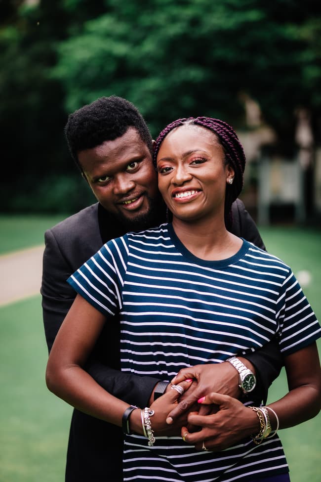 The couple stands closely, smiling warmly at the camera, with lush greenery in the background in Brisbane's City Botanic Gardens.