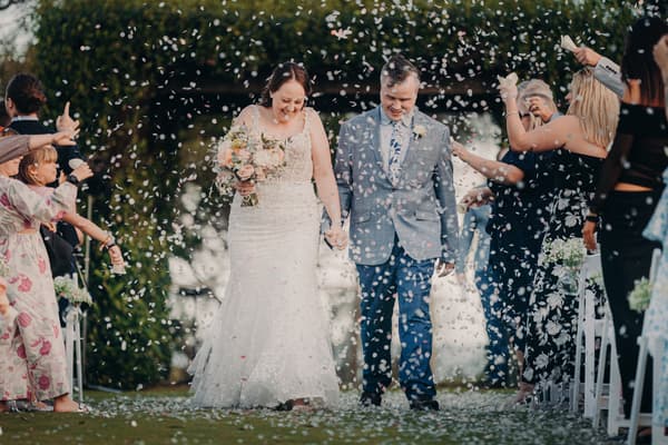 Bride Rebecca and groom Dale walk down the aisle at Sandstone Point Hotel — Rustic Arbour as guests throw flower petals.