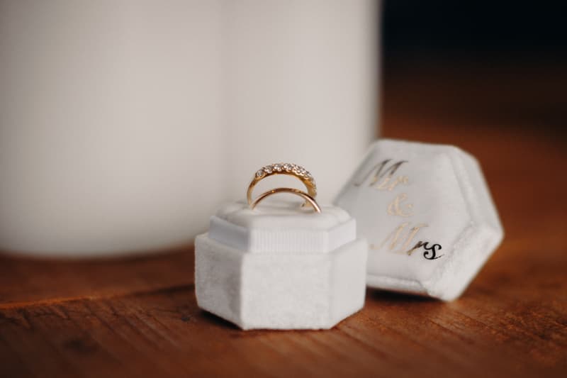 Close-up of two gold wedding rings placed on a white velvet ring box with the lid beside it embroidered with 'Mr & Mrs' at Preston Peak Winery Functions Centre.