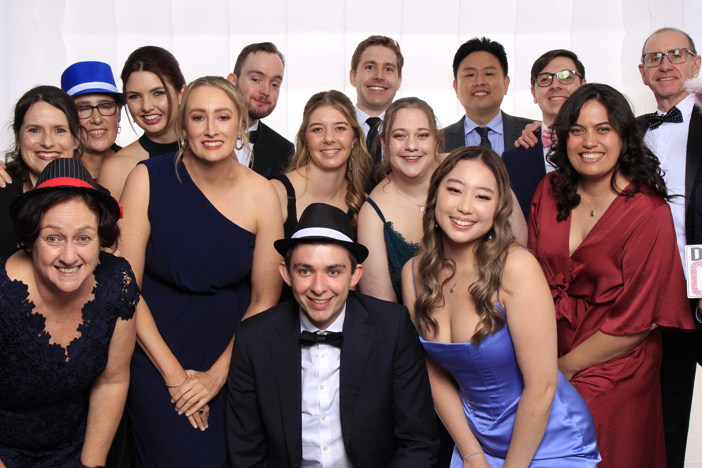 Group photo of guests in formal attire with fun hats and smiles.