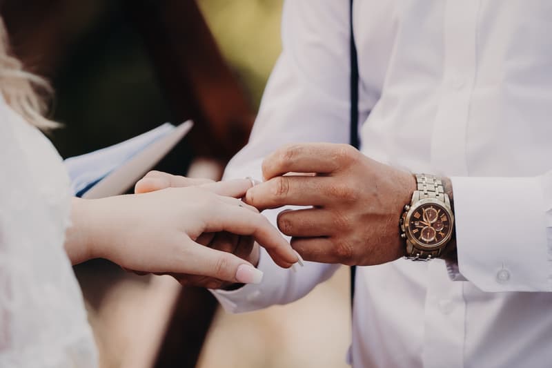 The groom places a ring on the bride's finger during the wedding ceremony at Ocean View Estates.