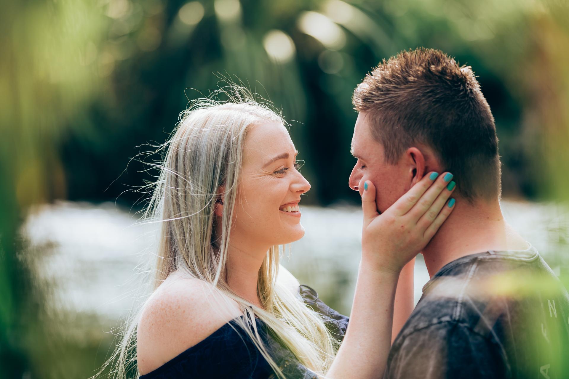 The couple smiling warmly, with one gently touching the other's face at City Botanic Gardens.