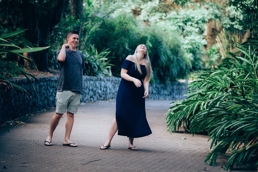 The couple laughing together on a path, surrounded by lush greenery at City Botanic Gardens.