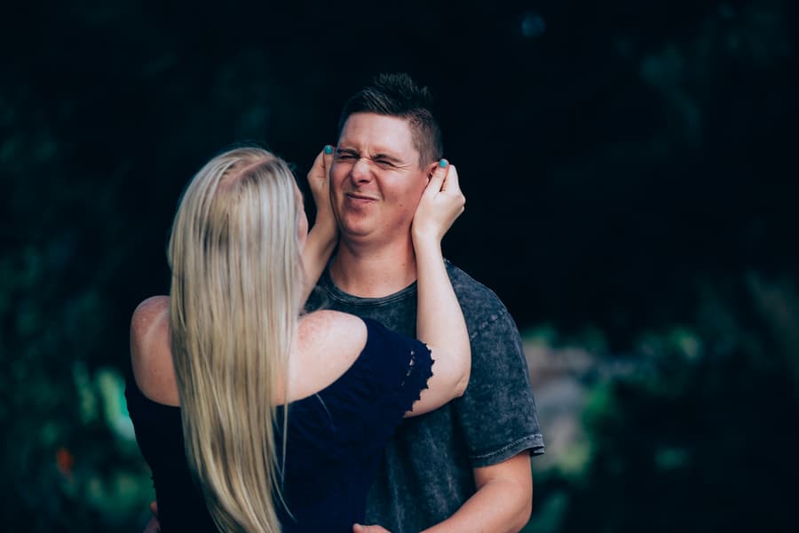 The couple playfully interacting, with one gently holding the other's face, both smiling.