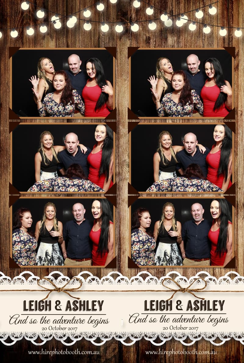 Group of smiling guests posing in a photo booth with playful expressions and props.