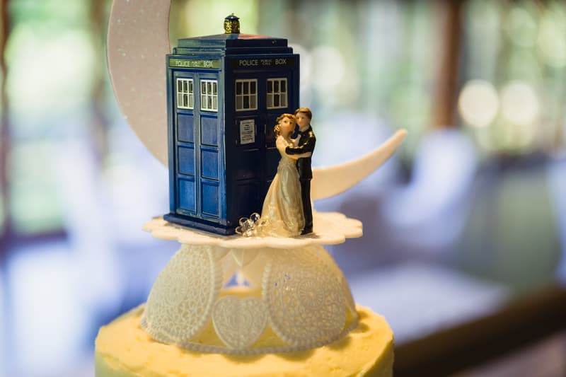 A wedding cake topper at Kwila Lodge featuring a miniature bride and groom figurine standing next to a blue police public call box model.
