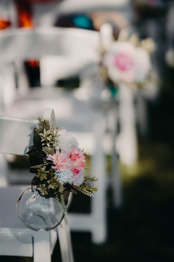 Close-up of floral decorations attached to white chairs arranged in rows at Sandstone Point Hotel — The Pavilion ceremony area.