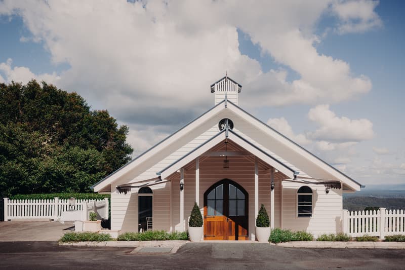 Exterior front view of the chapel building at Tiffany's Maleny with white picket fencing and a partly cloudy sky.