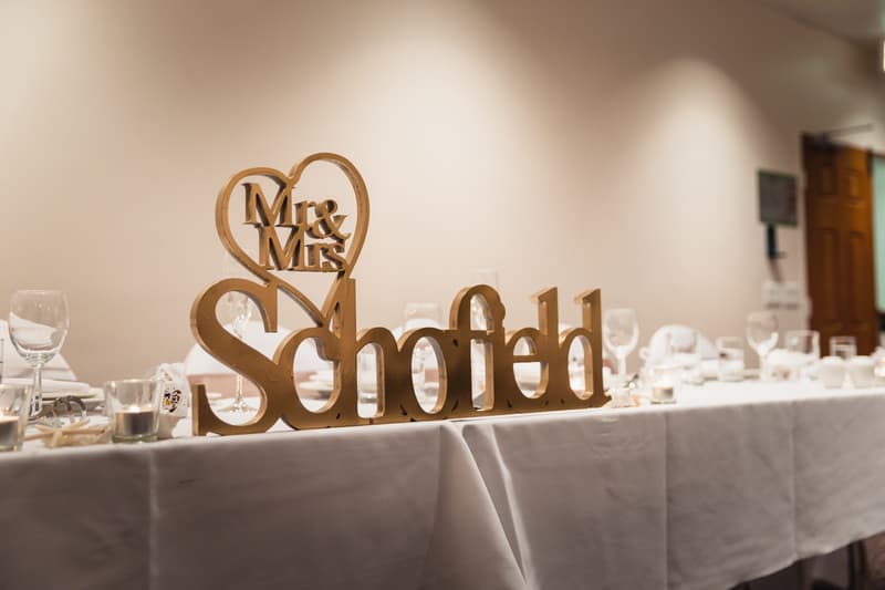 A reception table at Novotel Sunshine Coast Resort with a wooden sign reading 'Mr & Mrs Schofield' and set with glassware and candles.