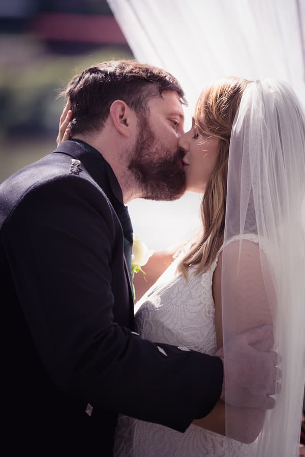 The bride Francesca and groom Ben share a kiss during their ceremony at Toowong Rowing Club by the Brisbane River's edge.