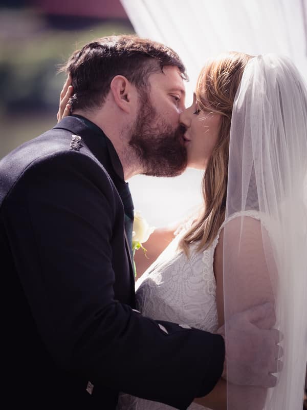 The bride Francesca and groom Ben share a kiss during their ceremony at Toowong Rowing Club by the Brisbane River's edge.